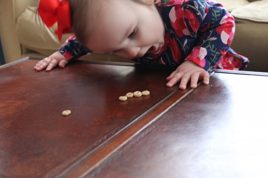 avery eating cheerios off table